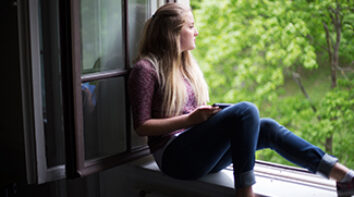 Photo of teenage girl looking out of window